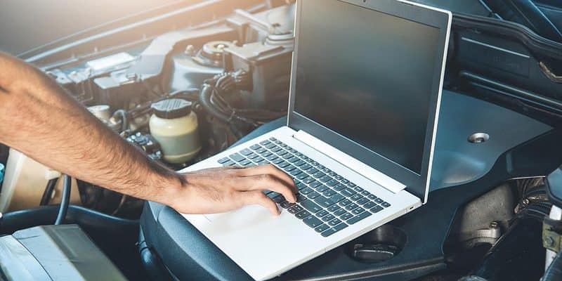 Laptop sitting on the open hood of a car