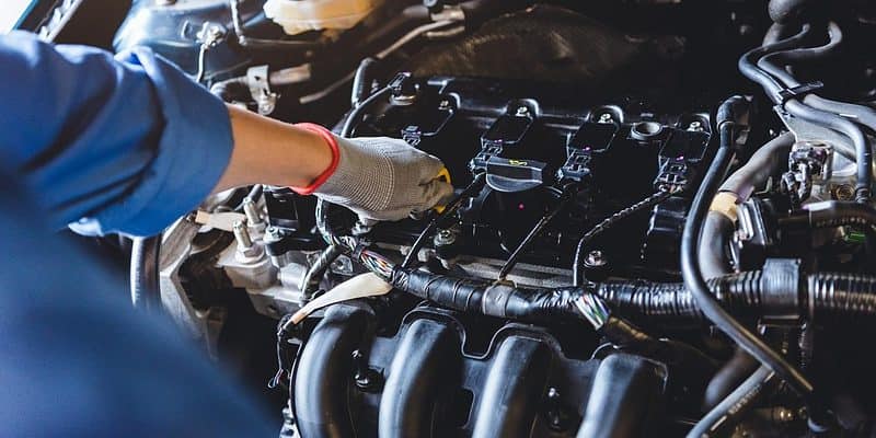 Person holding the engine oil dipstick handle of a car