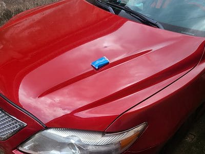 blue clay bar on the hood of a red 2009 Toyota Camry