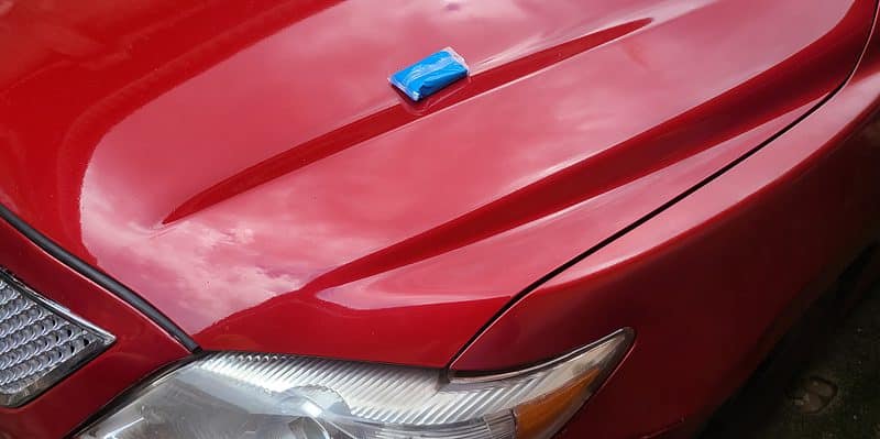 blue clay bar on the hood of a red 2009 Toyota Camry