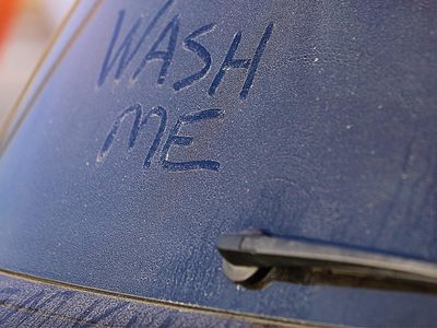 Dirty car with wash me sign