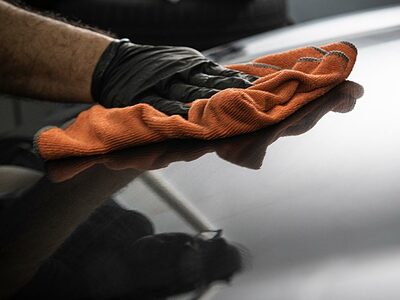 Using orange microfiber cloth to wipe a black car