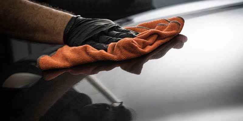 Using orange microfiber cloth to wipe a black car