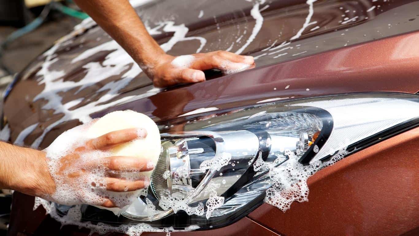 Hand washing a burgundy-colored car