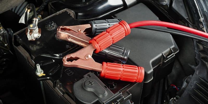 red and black jumper cable clamps on top of a car battery